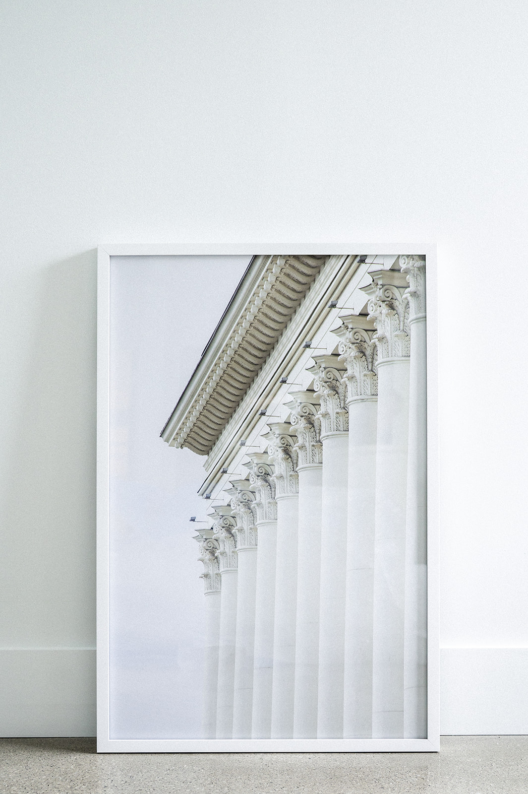 Large picture frame placed on ground, picture is of a marble building with large tall columbus