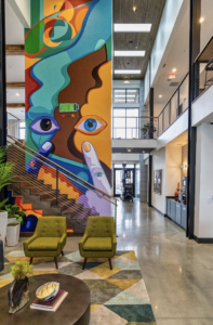 Colorful mural in multifamily complex clubhouse. Mural has many different colors and an eye design with fingers pointing to the eye. Abstract mural. Wide open spaces surrounding with natural lighting.