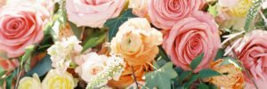 Arrangement of mixed florals including pink roses, peach colored roses, white baby's breath flowers, and ivy leaves