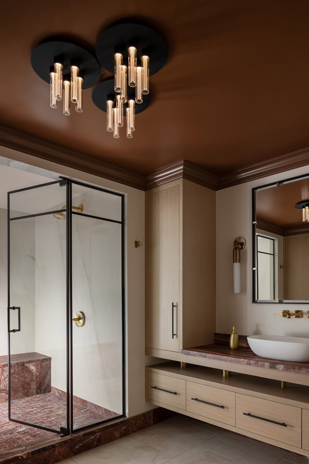 Modern bathroom with a glass shower enclosure, wall-mounted vanity with vessel sink, marble countertop, and contemporary ceiling lights against a brown ceiling.