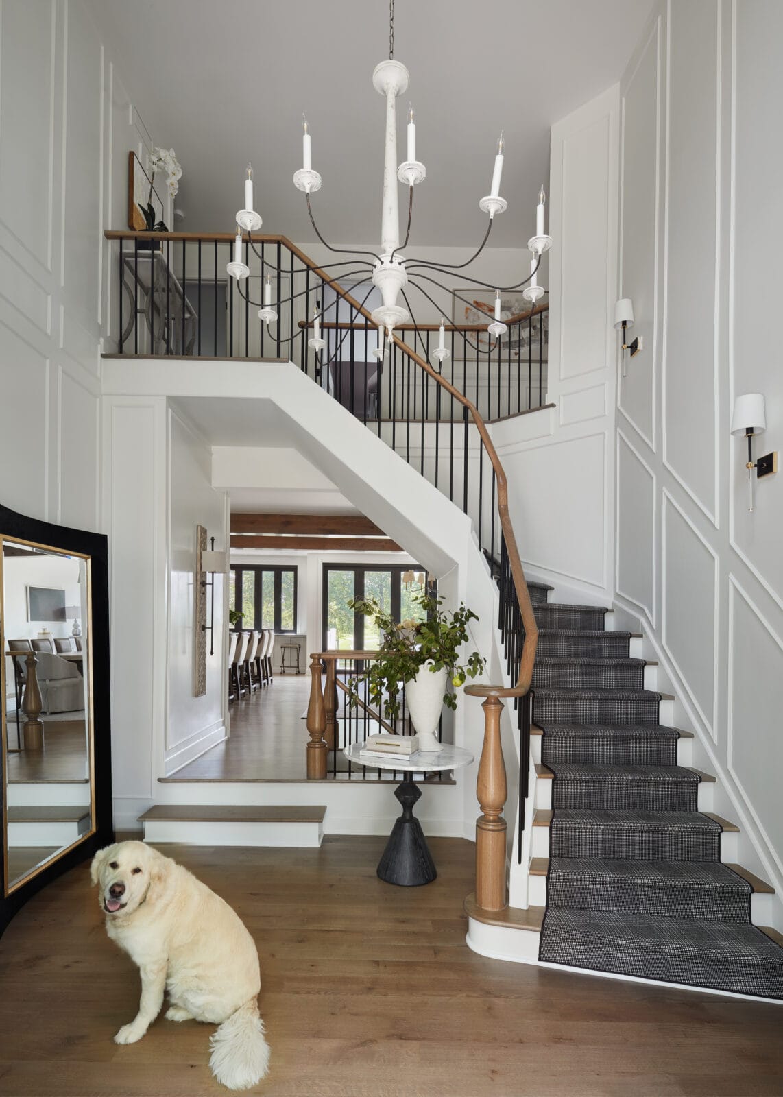 Elegant modern staircase with white walls and wooden accents, featuring a dog sitting on the hardwoo.