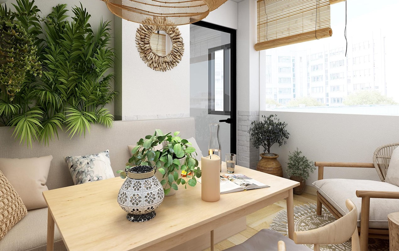 A sunlit room by Crimson Design Group features a wooden table, decorative candle, potted plant, cushioned seating, woven light fixture, greenery wall, and a large window with bamboo blinds.