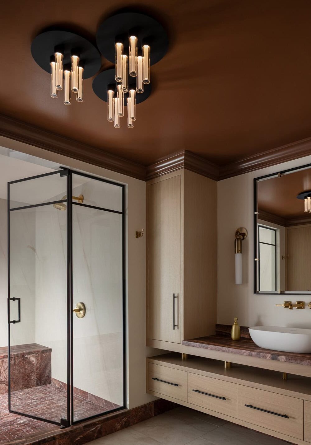 Modern bathroom with a glass shower enclosure, wall-mounted vanity with vessel sink, marble countertop, and contemporary ceiling lights against a brown ceiling.
