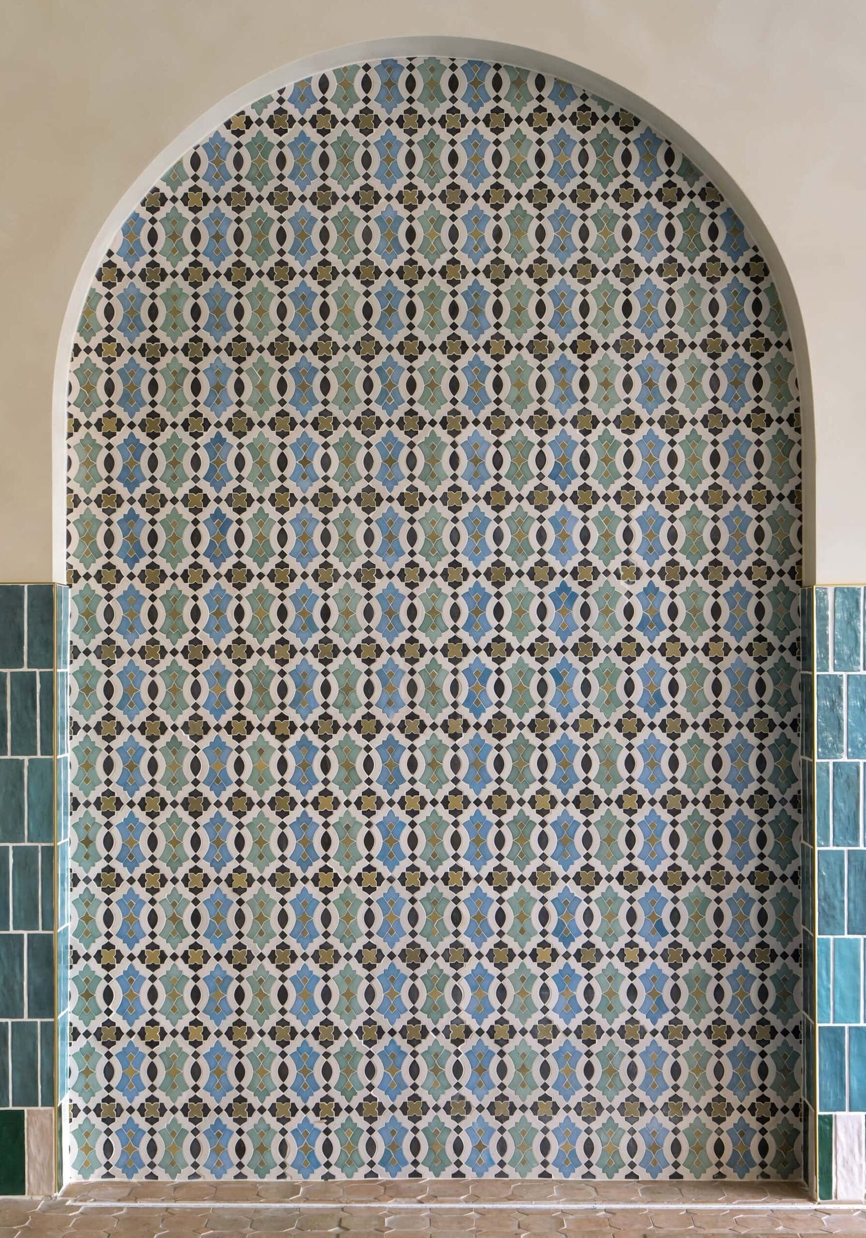 Arched wall alcove featuring intricate geometric and floral patterned tiles in blue, green, and brown, bordered by rectangular green tiles on both sides—an elegant touch inspired by retail design in Scottsdale, Arizona.