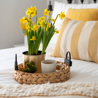 Yellow daffodils and a cup of tea on a tray in a light and bright bedroom