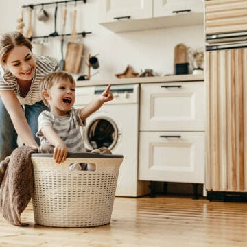 Happy family mother housewife and child son in laundry with washing machine
